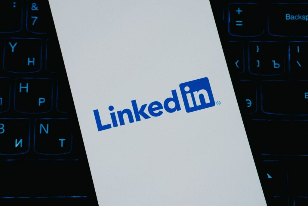 How to build thought leadership on LinkedIn - White screen displaying the LinkedIn logo in blue, placed on a dark computer keyboard background.
